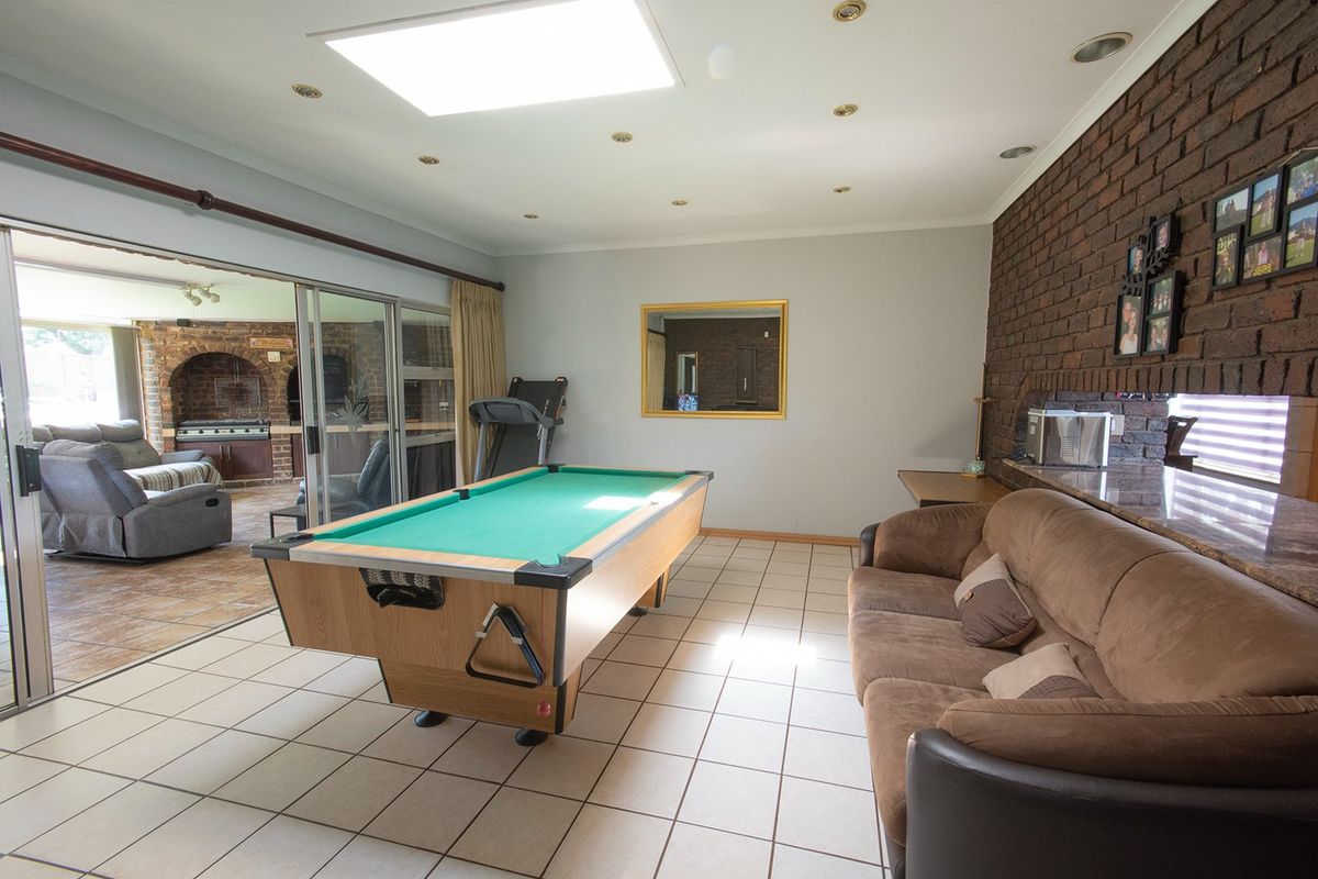 Spacious living area featuring a brick feature wall, tiled flooring, recessed ceiling lighting, and large sliding glass doors opening to an outdoor patio.