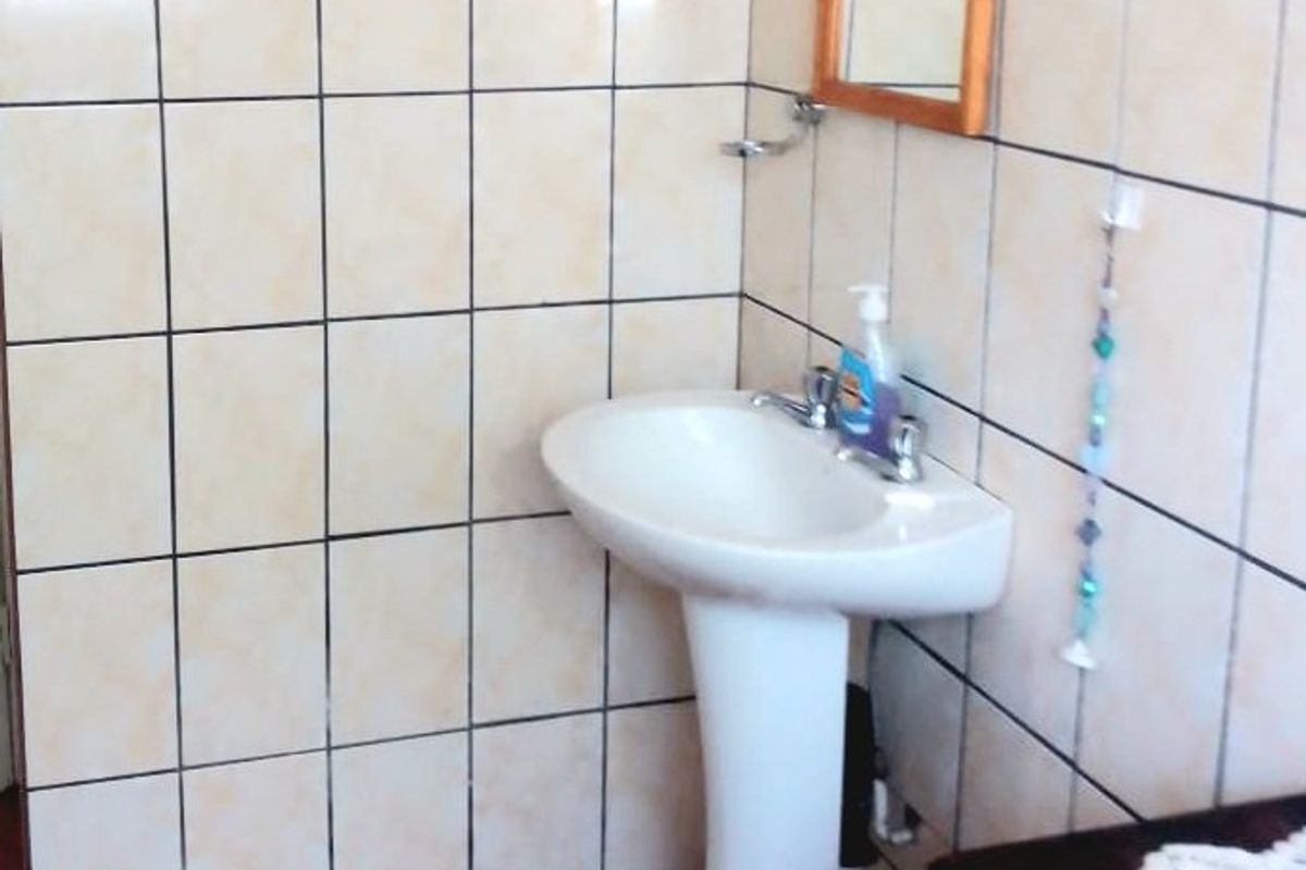 A functional bathroom featuring a pedestal basin, tiled walls, and tiled flooring.