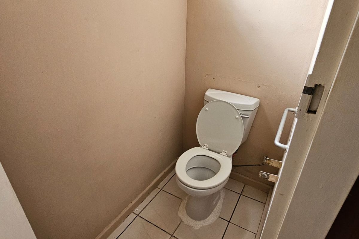 A compact, functional guest toilet featuring tiled flooring and a standard white ceramic toilet suite.