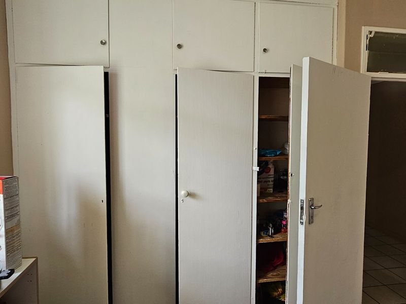 A bedroom featuring built-in floor-to-ceiling cupboards with white cabinetry and a doorway leading to an adjacent tiled area.