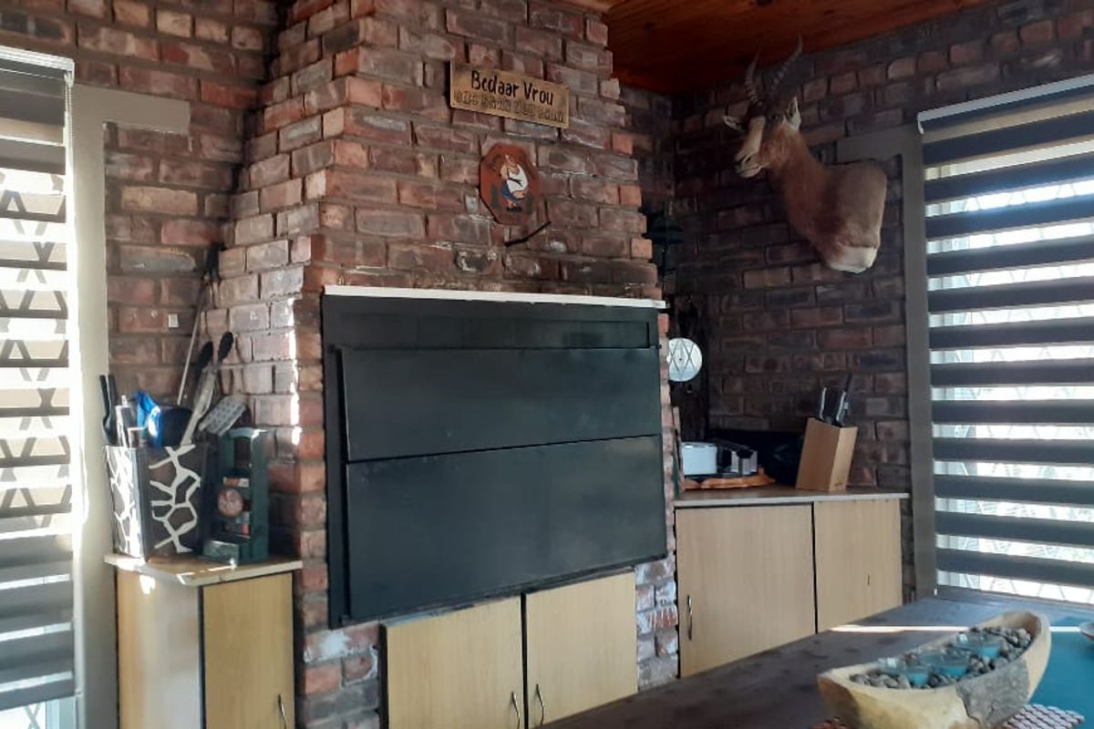Living area featuring a prominent exposed brick fireplace with a built-in braai and timber ceiling finishes.