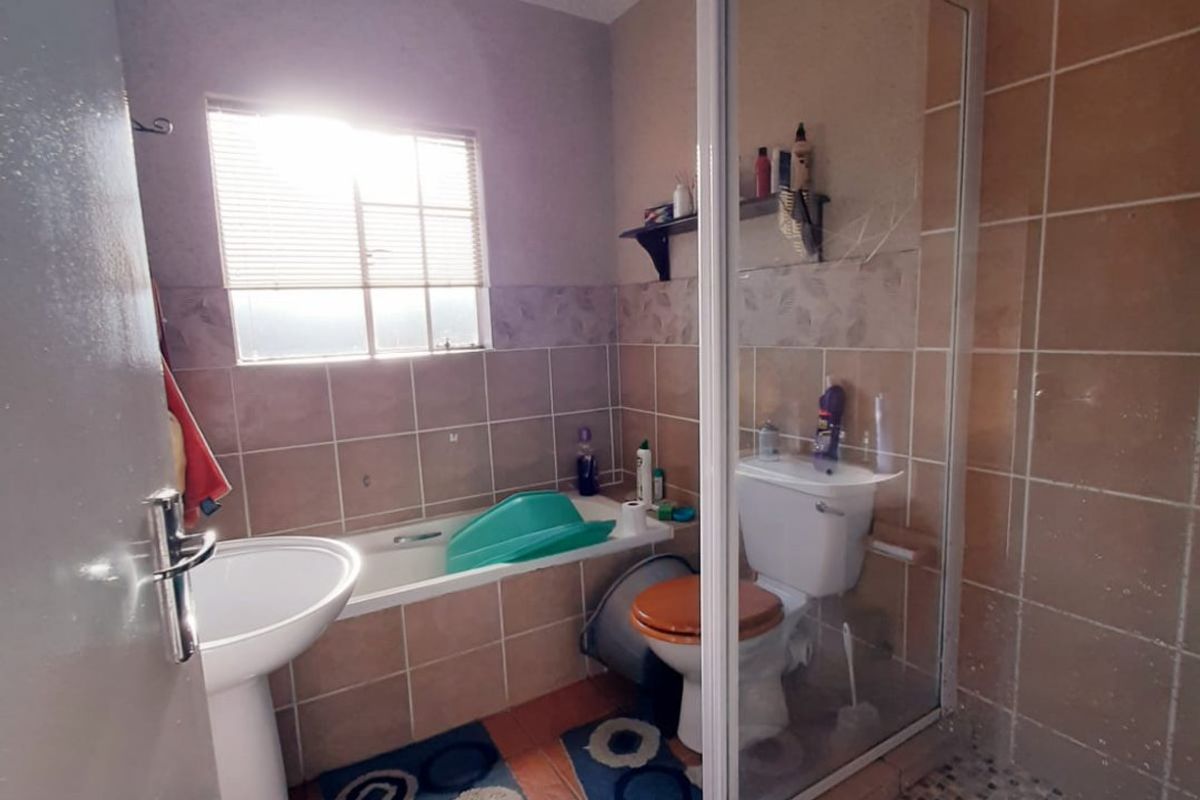 A functional bathroom featuring a pedestal basin, a built-in bathtub, and a separate glass-enclosed shower with tiled walls and flooring.