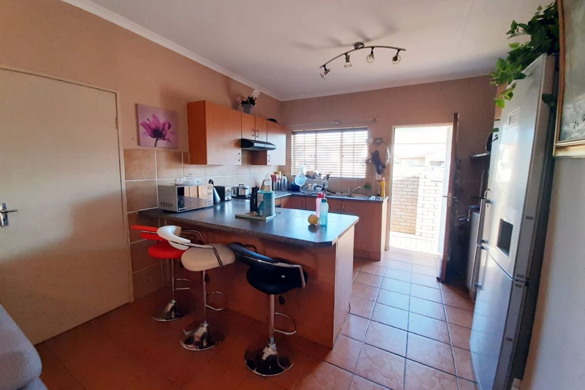 Functional kitchen featuring a breakfast bar, built-in cabinetry, tiled flooring, and direct access to an outdoor area.