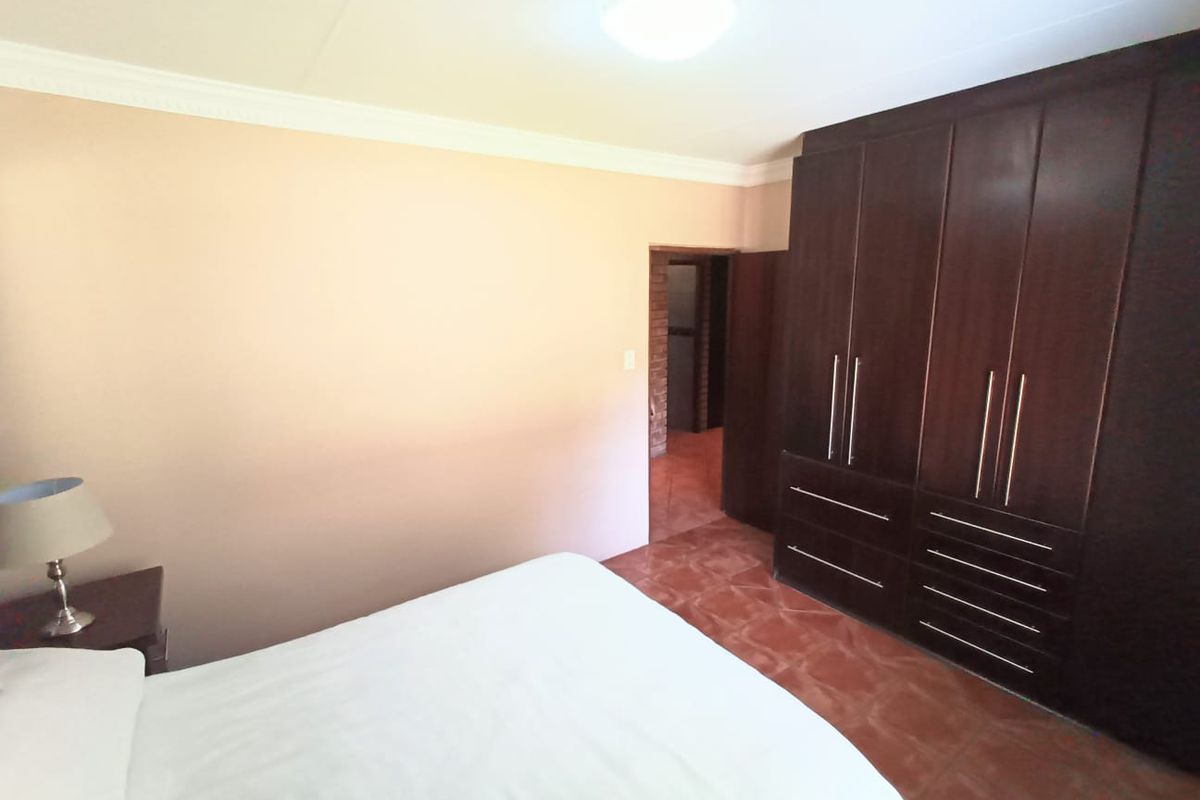 A bedroom featuring dark wood built-in cupboards, tiled flooring, and crown molding, providing ample storage space.