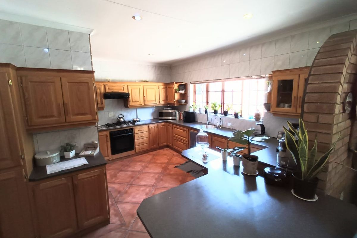 Spacious kitchen featuring traditional timber cabinetry, dark countertops, tiled flooring, and a distinctive brick archway detail.