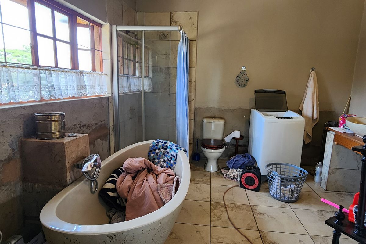A functional bathroom featuring a freestanding bathtub, a glass-enclosed shower, a toilet, and tiled flooring with unfinished wall surfaces.