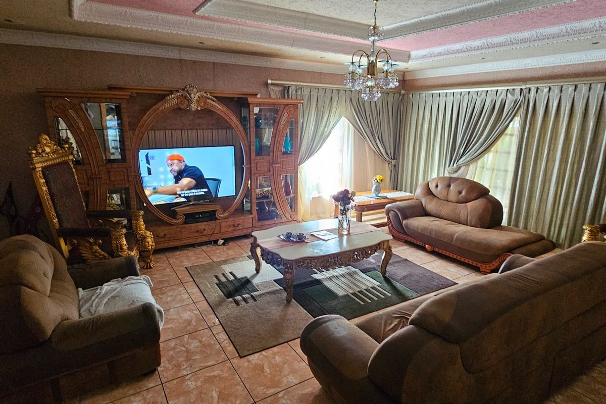 Spacious living room featuring decorative ceiling molding, a crystal chandelier, and tiled flooring, providing a traditional and formal atmosphere.