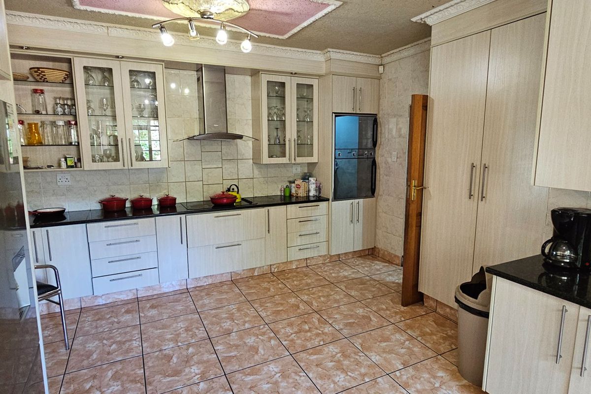 A functional kitchen featuring light wood cabinetry, black granite countertops, a built-in oven, and a stainless steel extractor fan.