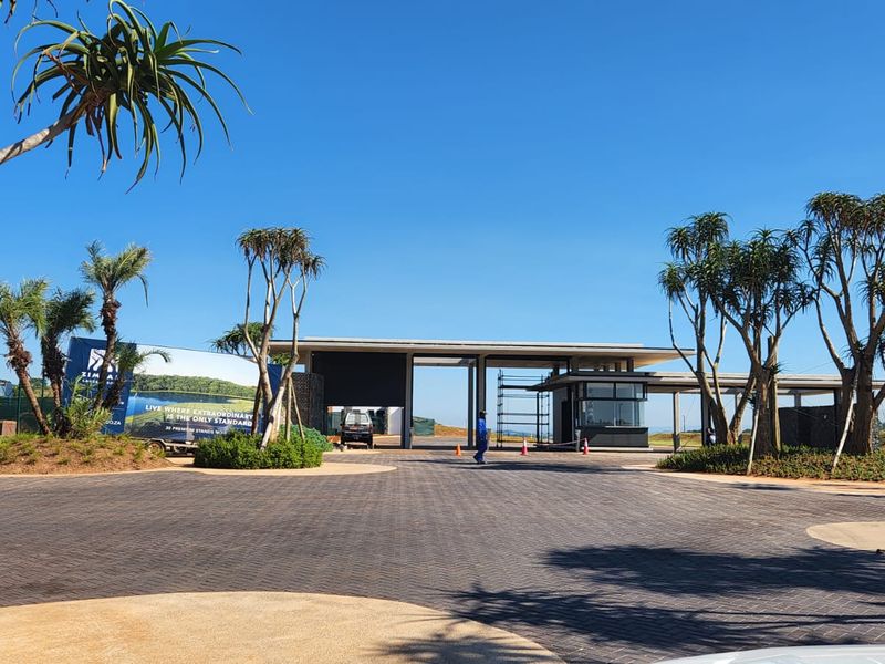 The main entrance and security gatehouse of the estate, featuring a paved driveway and landscaped surroundings.