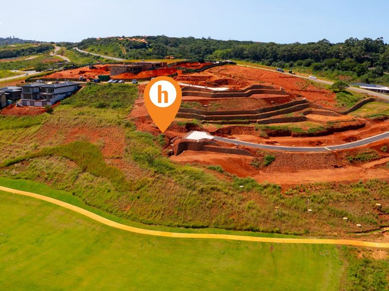 Aerial view of a residential development site featuring terraced earthworks, retaining walls, and newly constructed paved access roads within a landscaped estate.
