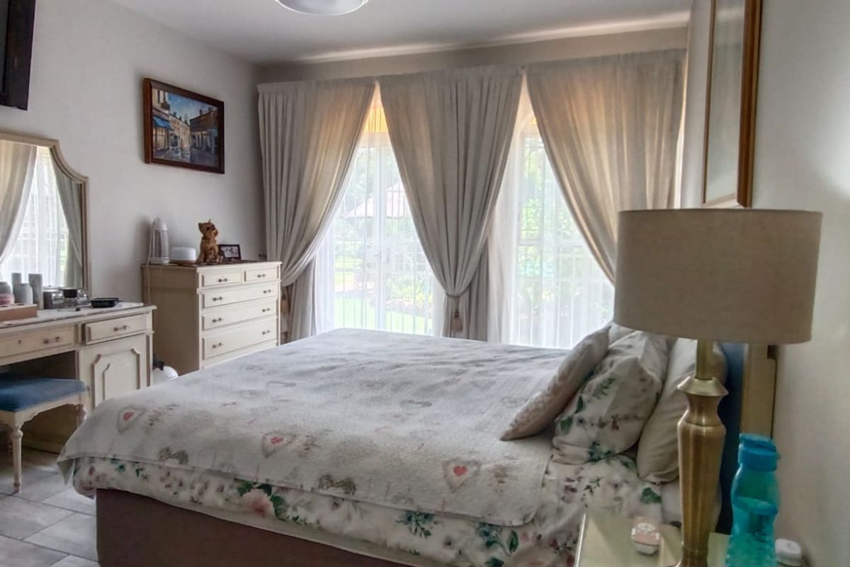 A well-lit bedroom featuring tiled flooring and large glass sliding doors that provide access to the garden area.