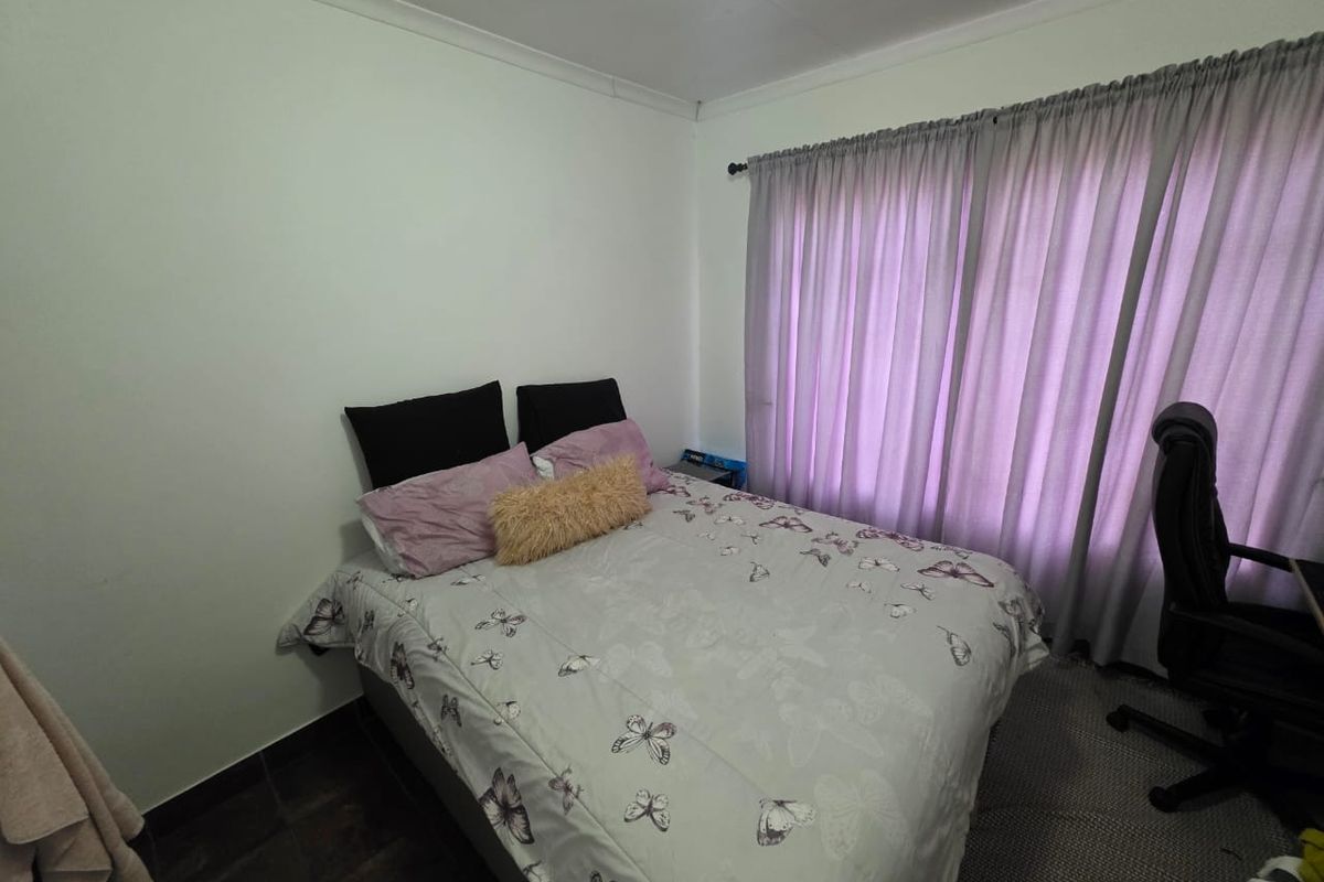 A functional bedroom featuring tiled flooring, neutral walls, and window curtains.