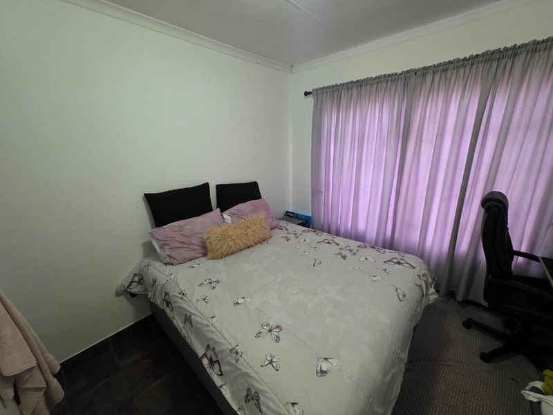 A functional bedroom featuring tiled flooring, neutral walls, and window curtains.
