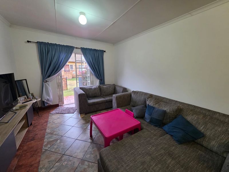 A living room featuring tiled flooring and a sliding glass door providing access to the outdoor area.