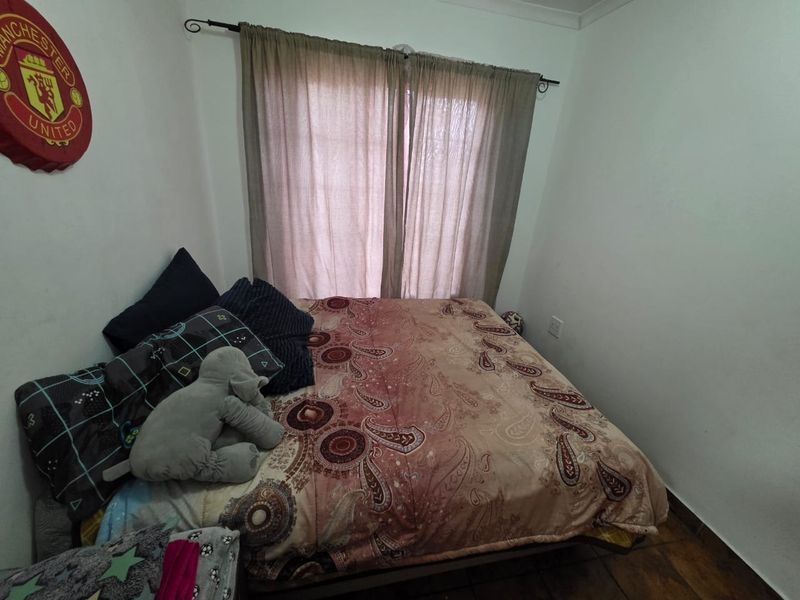 A standard bedroom featuring neutral walls, tiled flooring, and a window dressed with a curtain rod.