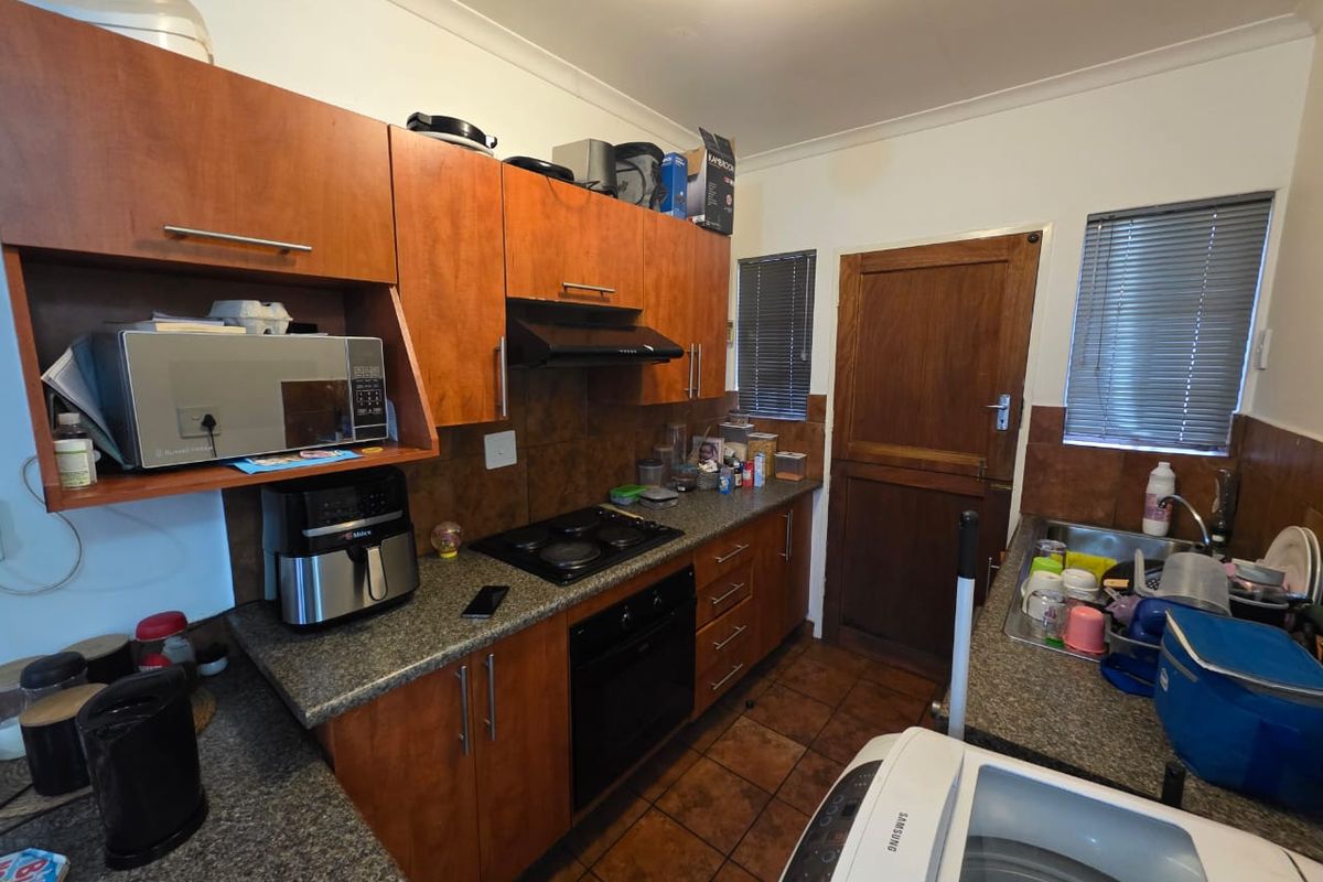 Functional kitchen featuring wood-finish cabinetry, built-in oven and hob, tiled backsplash, and direct access to an exterior door.