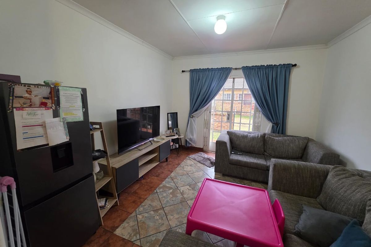 A living room featuring tiled flooring and a sliding glass door providing access to the exterior, with neutral walls and standard ceiling finishes.