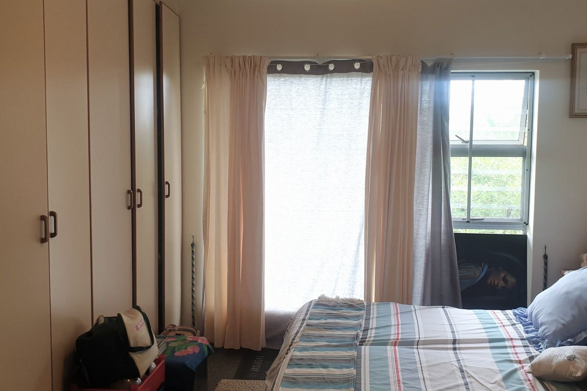 A bedroom featuring built-in floor-to-ceiling cabinetry and a window with natural light.
