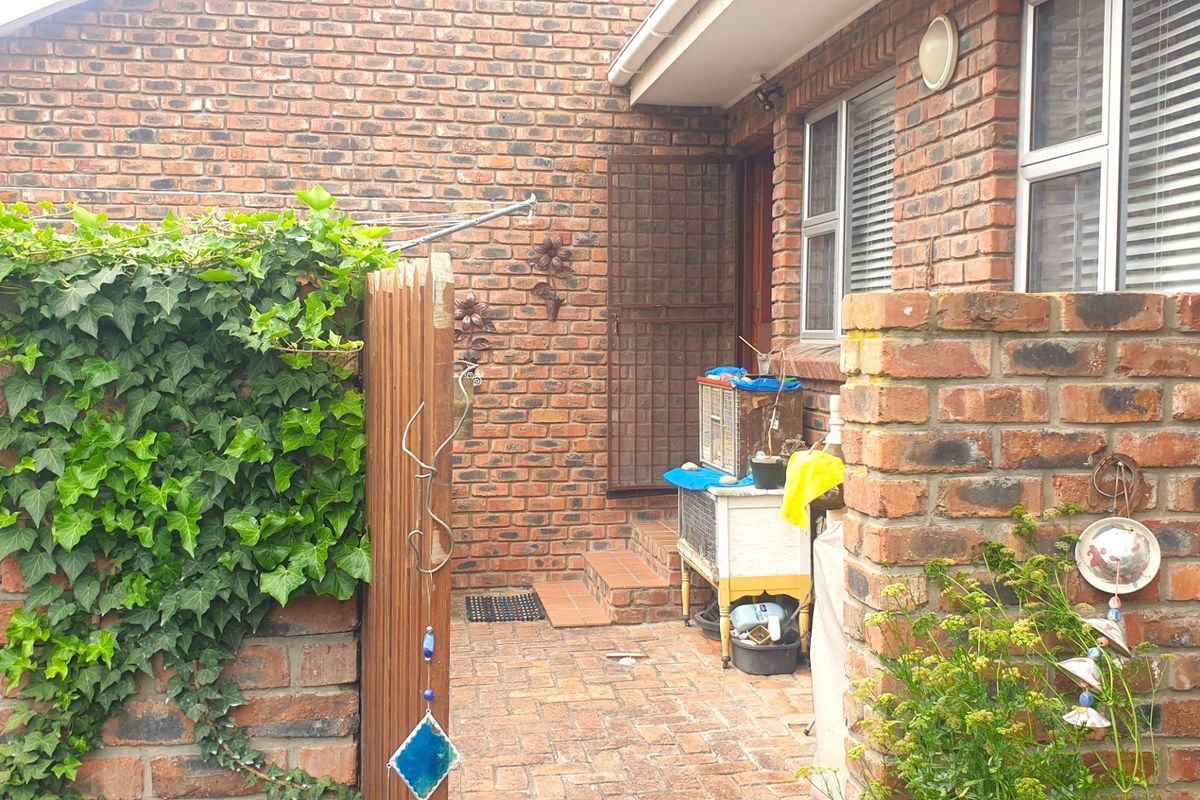 A private rear courtyard area featuring exposed face-brick walls, paved flooring, and a secure gated entrance.