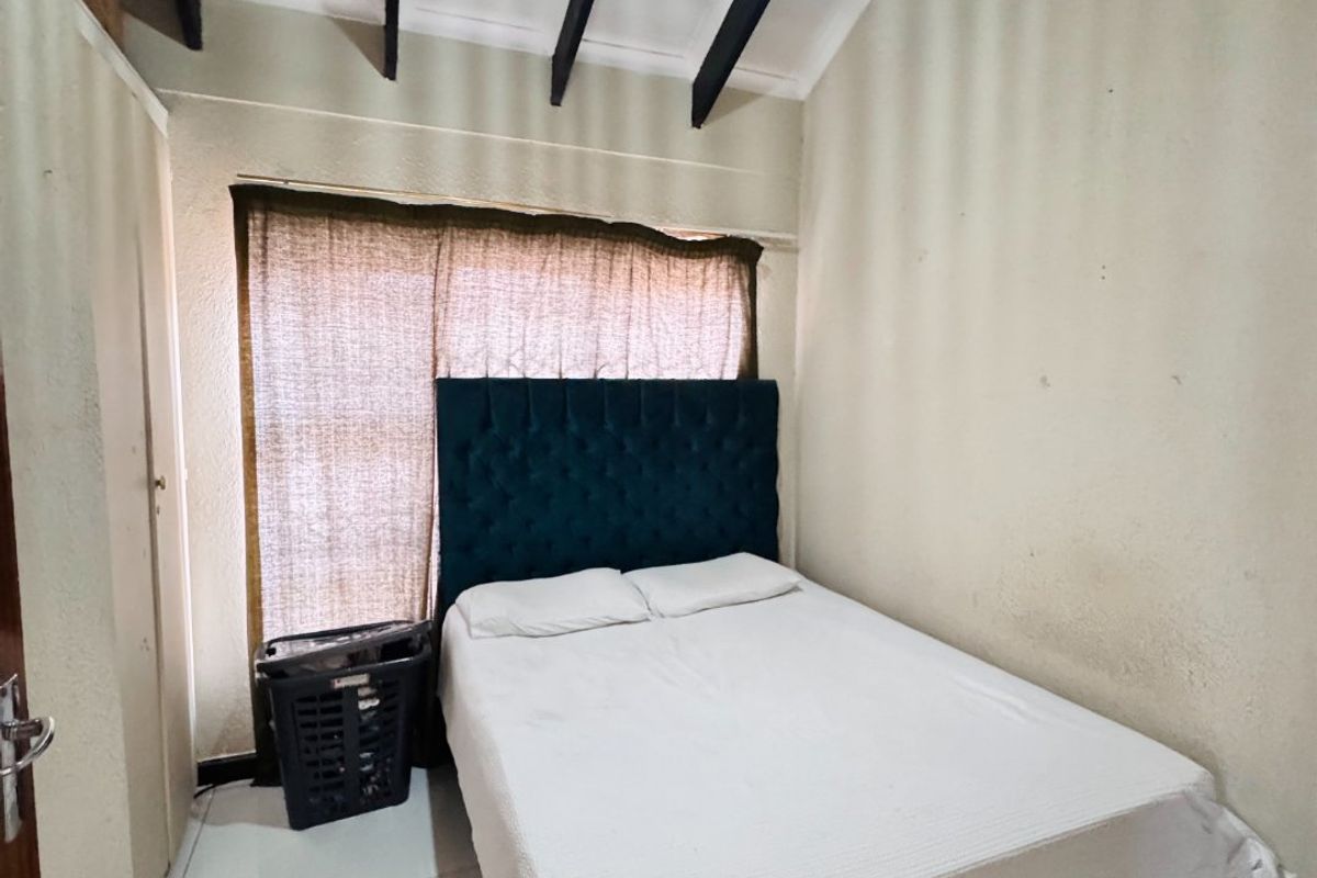 A bedroom featuring high vaulted ceilings with exposed beams, tiled flooring, and a built-in cupboard.