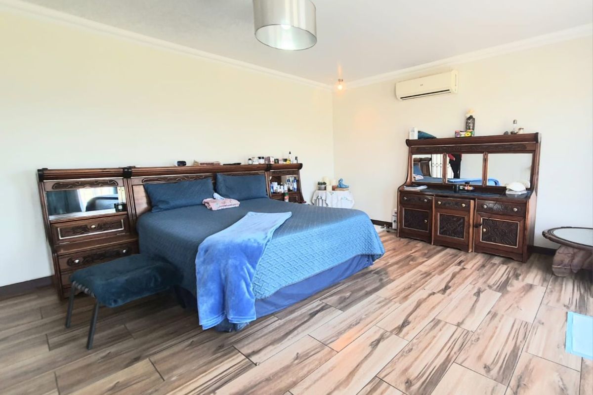 Spacious bedroom featuring wood-look tile flooring, a wall-mounted air conditioning unit, and neutral wall finishes.