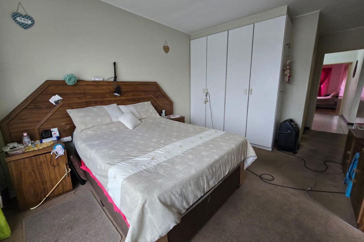 A bedroom featuring built-in cupboards and carpeted flooring, offering a functional space with potential for modern updates.