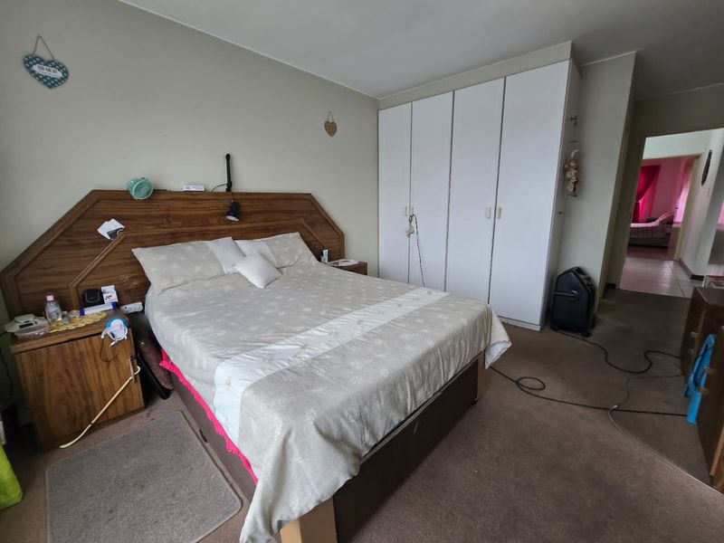 A bedroom featuring built-in cupboards and carpeted flooring, offering a functional space with potential for modern updates.
