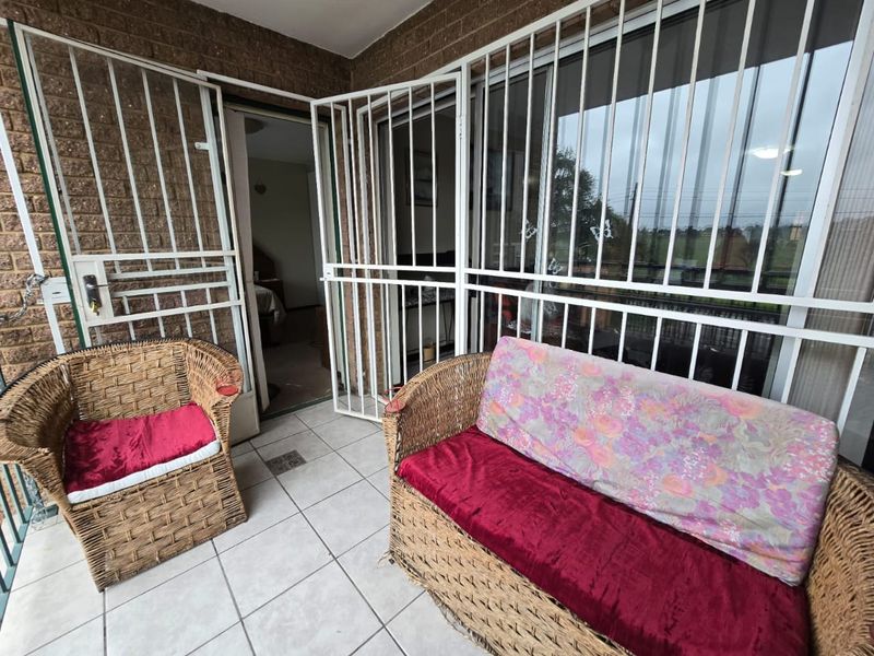 A covered balcony area featuring tiled flooring, brick wall finishes, and secure metal security gates and bars.