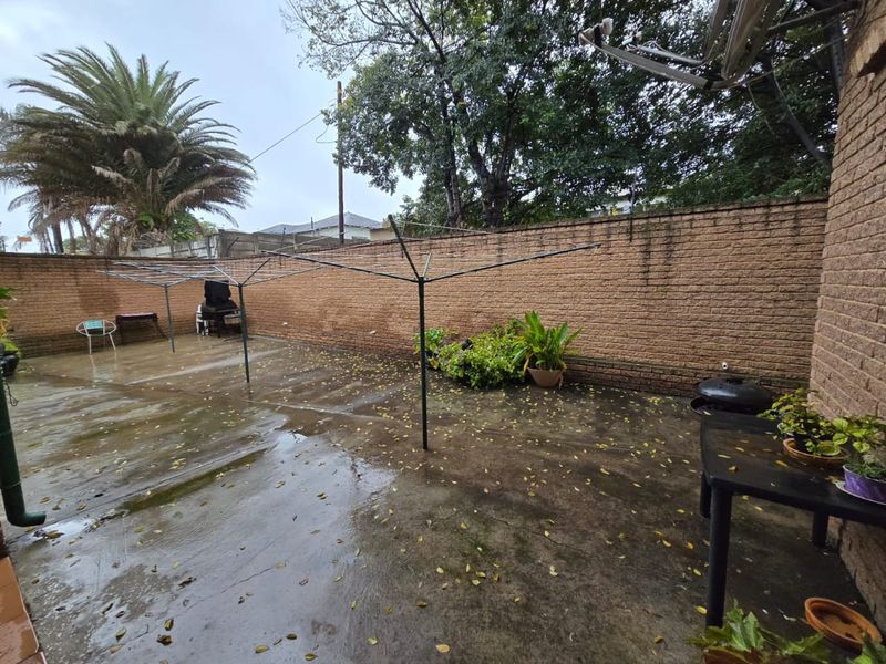 A paved rear courtyard area featuring a brick boundary wall and a rotary clothesline, offering a functional outdoor space.