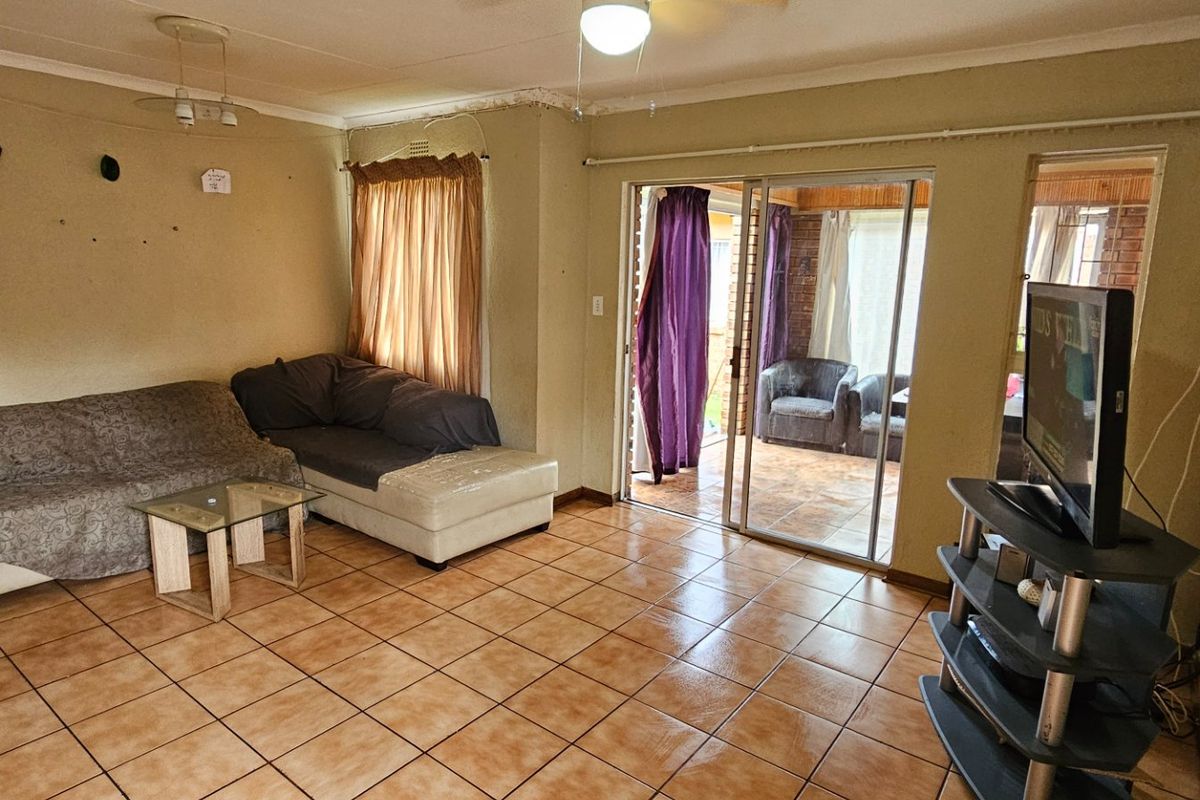 Living room featuring ceramic floor tiles and sliding glass doors providing access to an enclosed patio area.