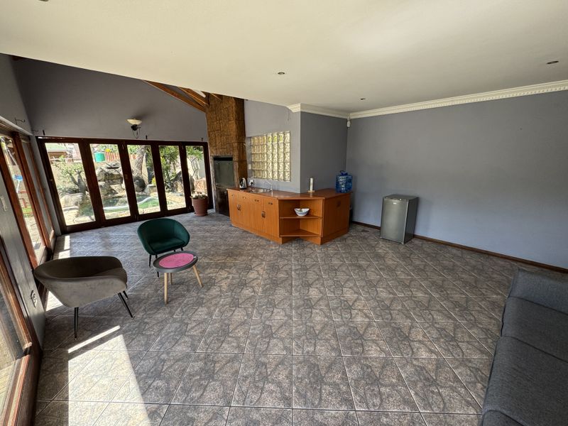 Spacious open-plan living area featuring a built-in bar with sink, glass block accents, fireplace, and large timber folding doors opening to the garden.