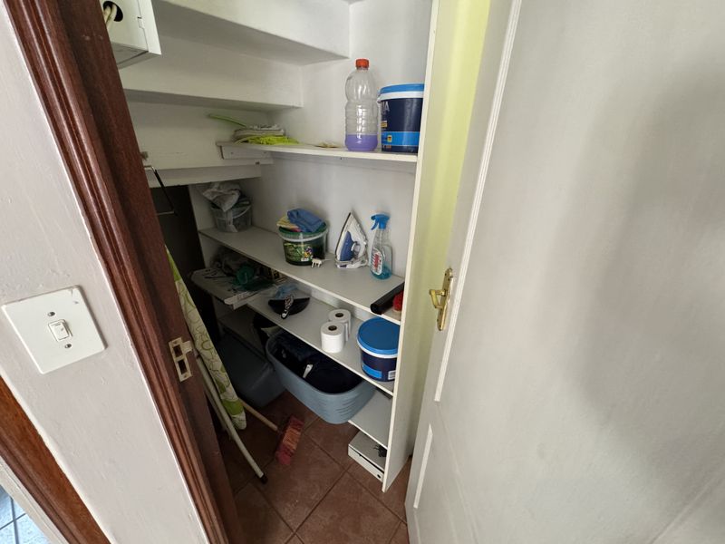 A functional utility storage closet featuring built-in shelving and tiled flooring, providing practical space for household organization and storage.