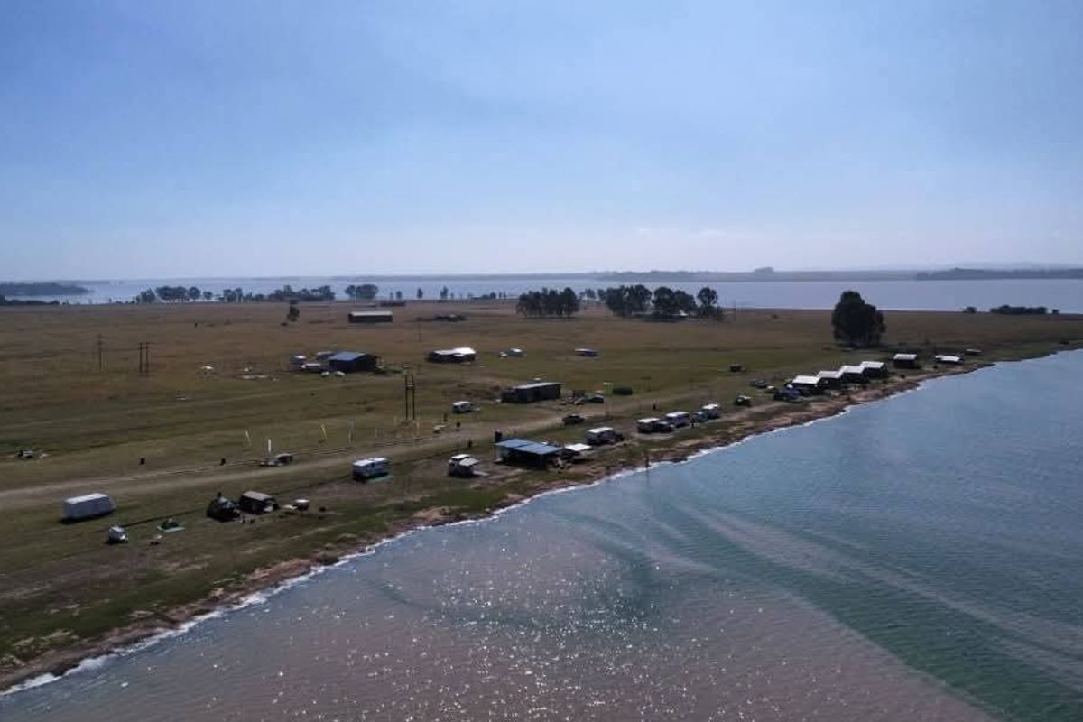 Aerial view of the farm property featuring extensive waterfront access, open grazing land, and various outbuildings along the shoreline.