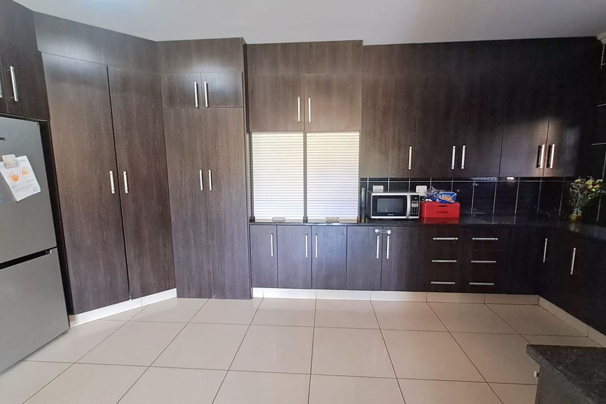 A functional kitchen featuring dark wood-grain cabinetry, granite countertops, and tiled flooring, providing ample storage and workspace.