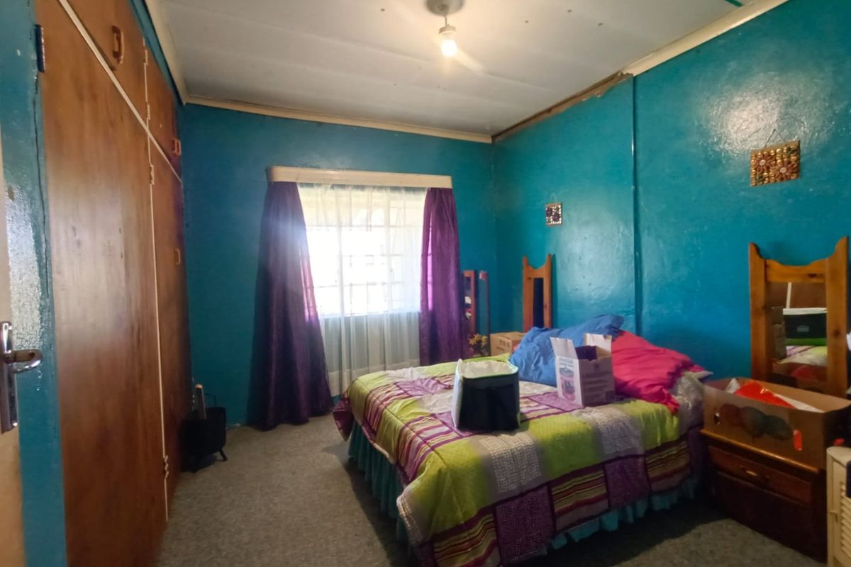 A bedroom featuring built-in wooden cupboards, carpeted flooring, and a window with natural light.
