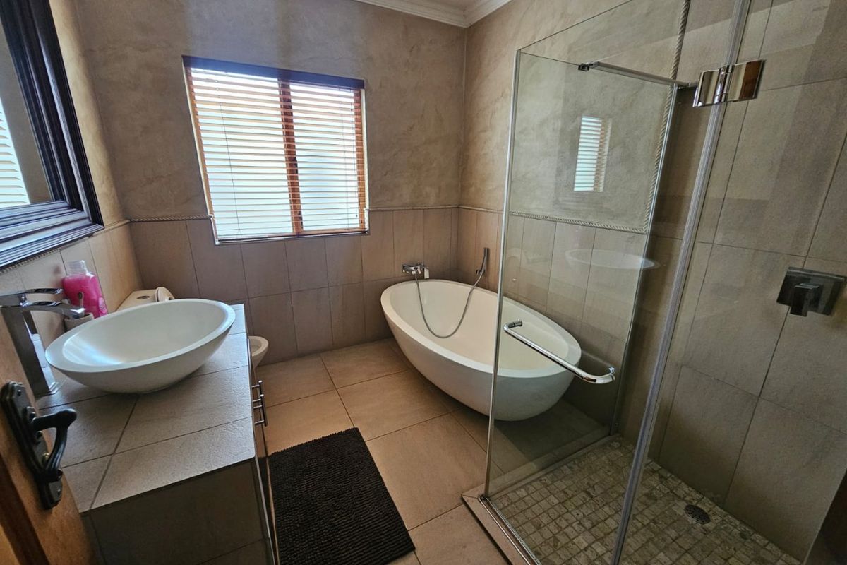 Modern bathroom featuring a freestanding bathtub, a glass-enclosed shower, and a vessel sink vanity with tiled walls and flooring.