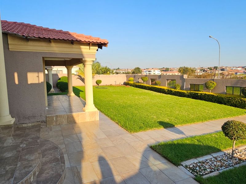 Spacious rear garden featuring a covered patio with tiled flooring, well-maintained lawn, and perimeter boundary walling.