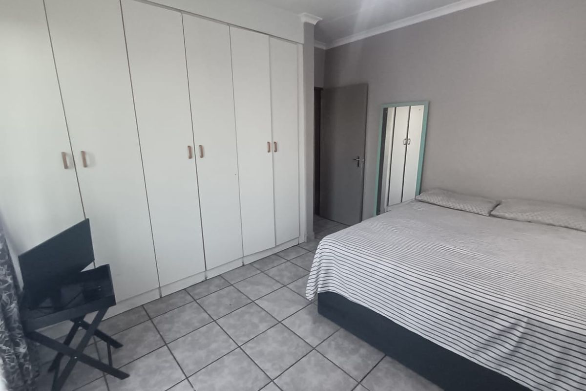 A bedroom featuring built-in floor-to-ceiling wardrobes and tiled flooring.