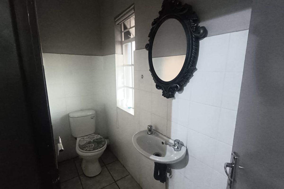 A functional guest bathroom featuring a wall-mounted basin, a standard toilet, and tiled wall finishes.