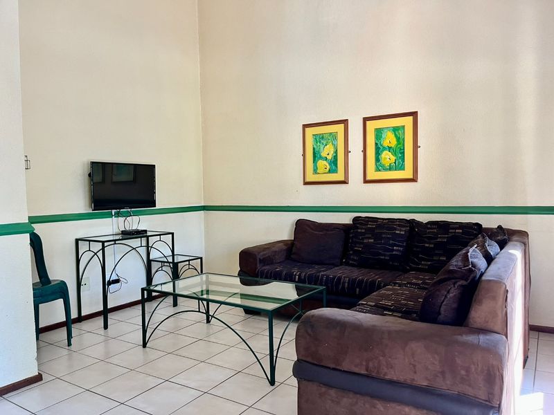 A living room featuring tiled flooring and a decorative chair rail, providing a functional and neutral space.