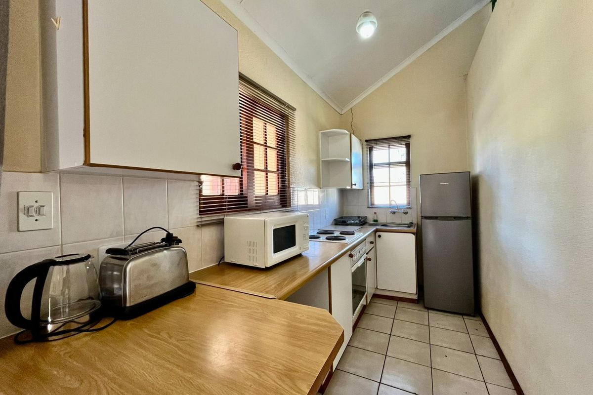 A compact kitchen featuring laminate countertops, built-in cabinetry, a built-in oven with hob, and tiled flooring, offering a functional layout for daily use.