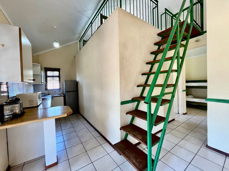 Open plan kitchen area featuring tiled flooring, built-in cabinetry, and a prominent metal staircase leading to a mezzanine level.