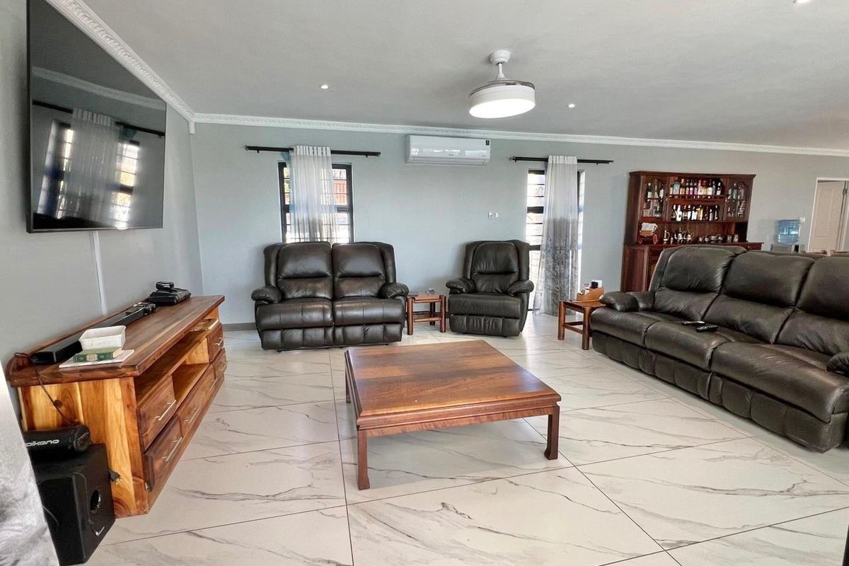 Spacious living room featuring large-format marble-look floor tiles, crown molding, recessed lighting, and a wall-mounted split-system air conditioner.