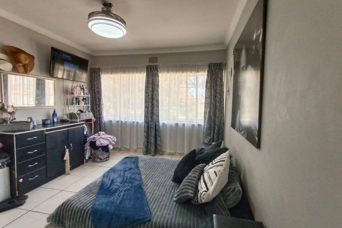 A bedroom featuring tiled flooring, large windows with curtain treatments, and a central ceiling light fixture.