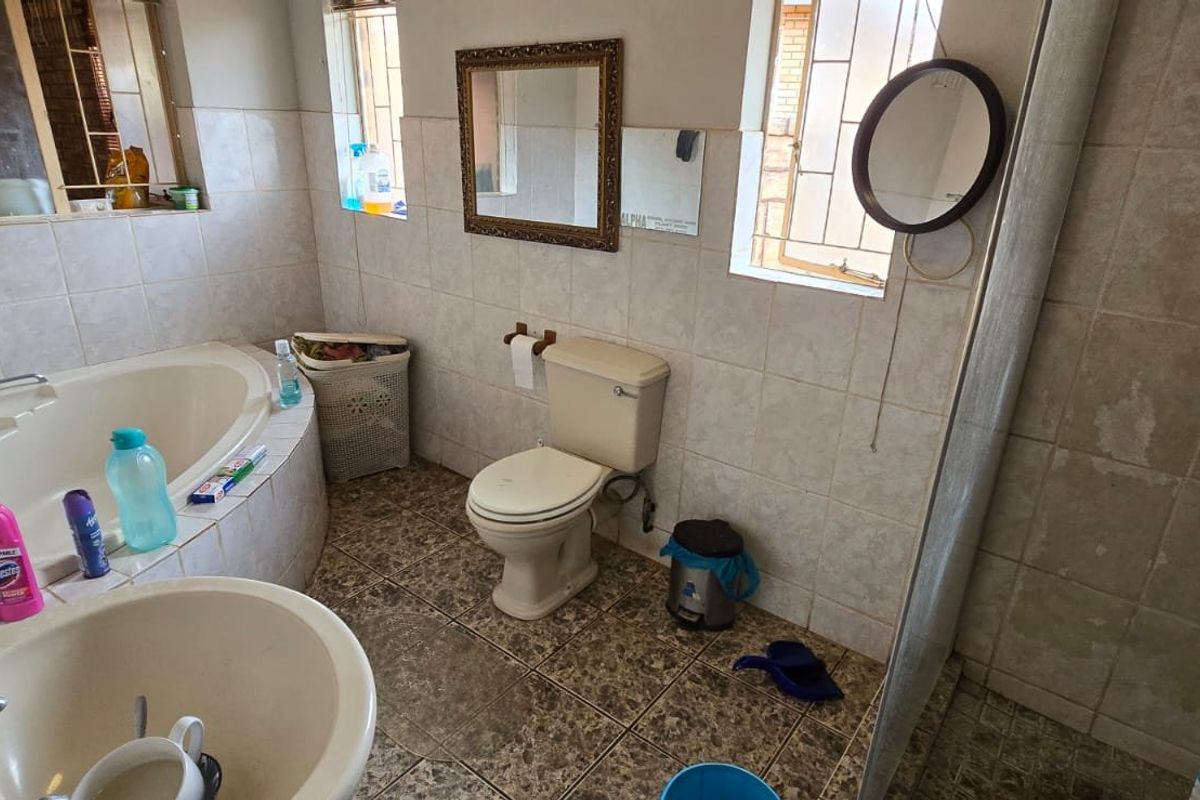 A dated bathroom featuring a corner bathtub, a separate shower, and a toilet, with neutral wall tiling and patterned floor tiles.