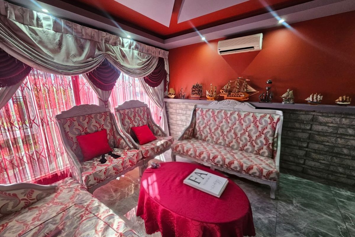 A living room featuring a decorative tray ceiling, wall-mounted air conditioning unit, and stone-cladding feature wall.