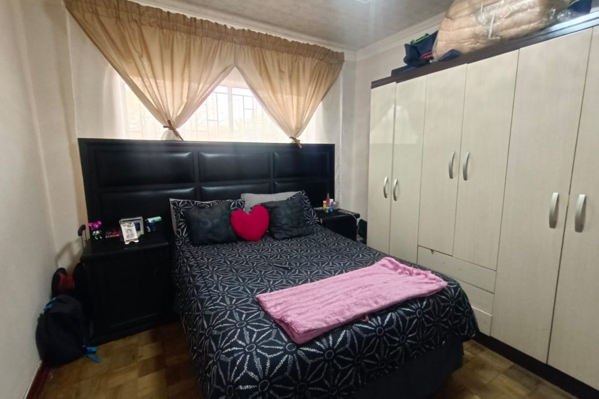 A functional bedroom featuring built-in cabinetry and parquet flooring, providing ample storage space and a comfortable layout.