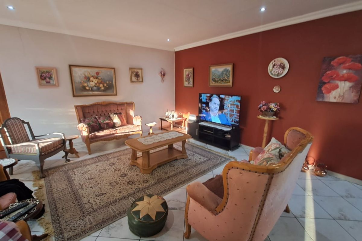 A spacious living room featuring tiled flooring, recessed ceiling lighting, and a prominent accent wall.