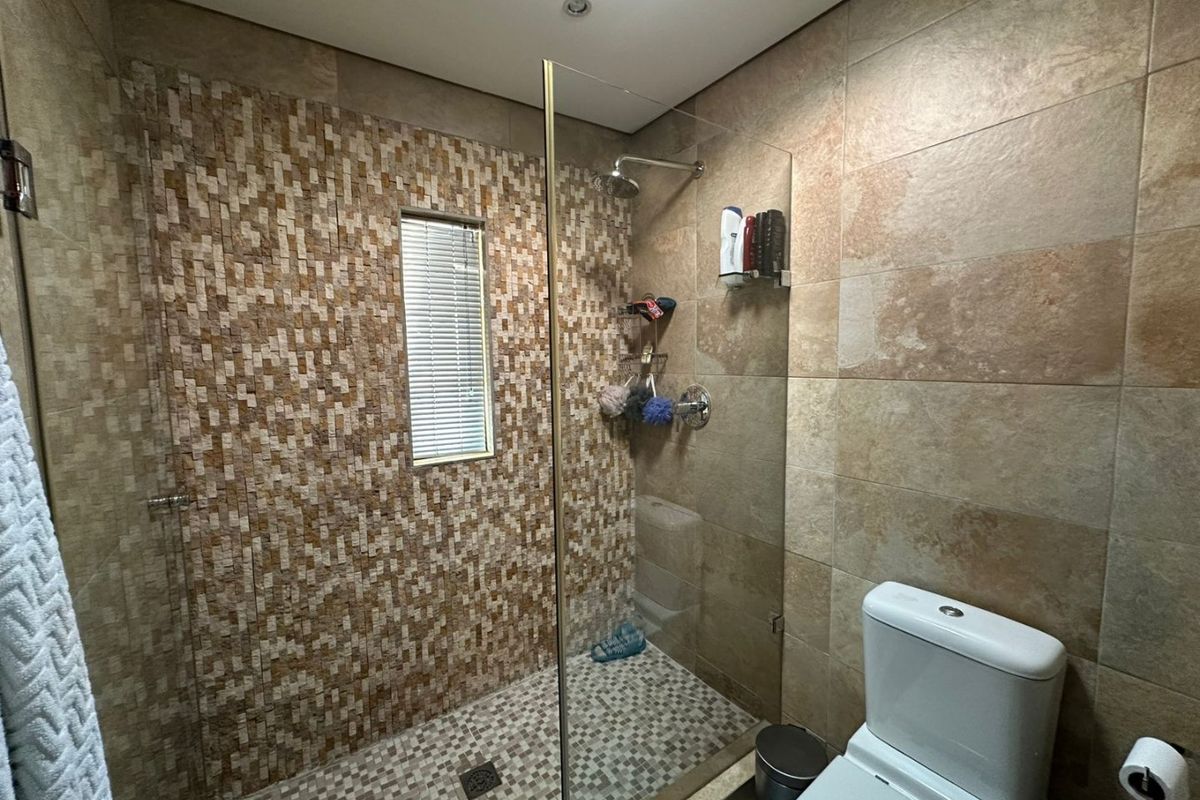 Modern bathroom featuring a walk-in shower with glass enclosure, mosaic tile accents, and a contemporary toilet.
