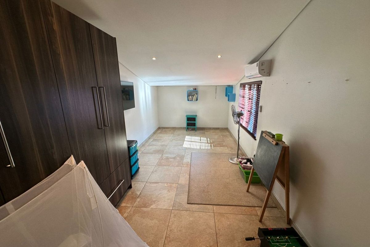 A bedroom featuring built-in dark wood cabinetry, tiled flooring, recessed ceiling lighting, and a wall-mounted air conditioning unit.